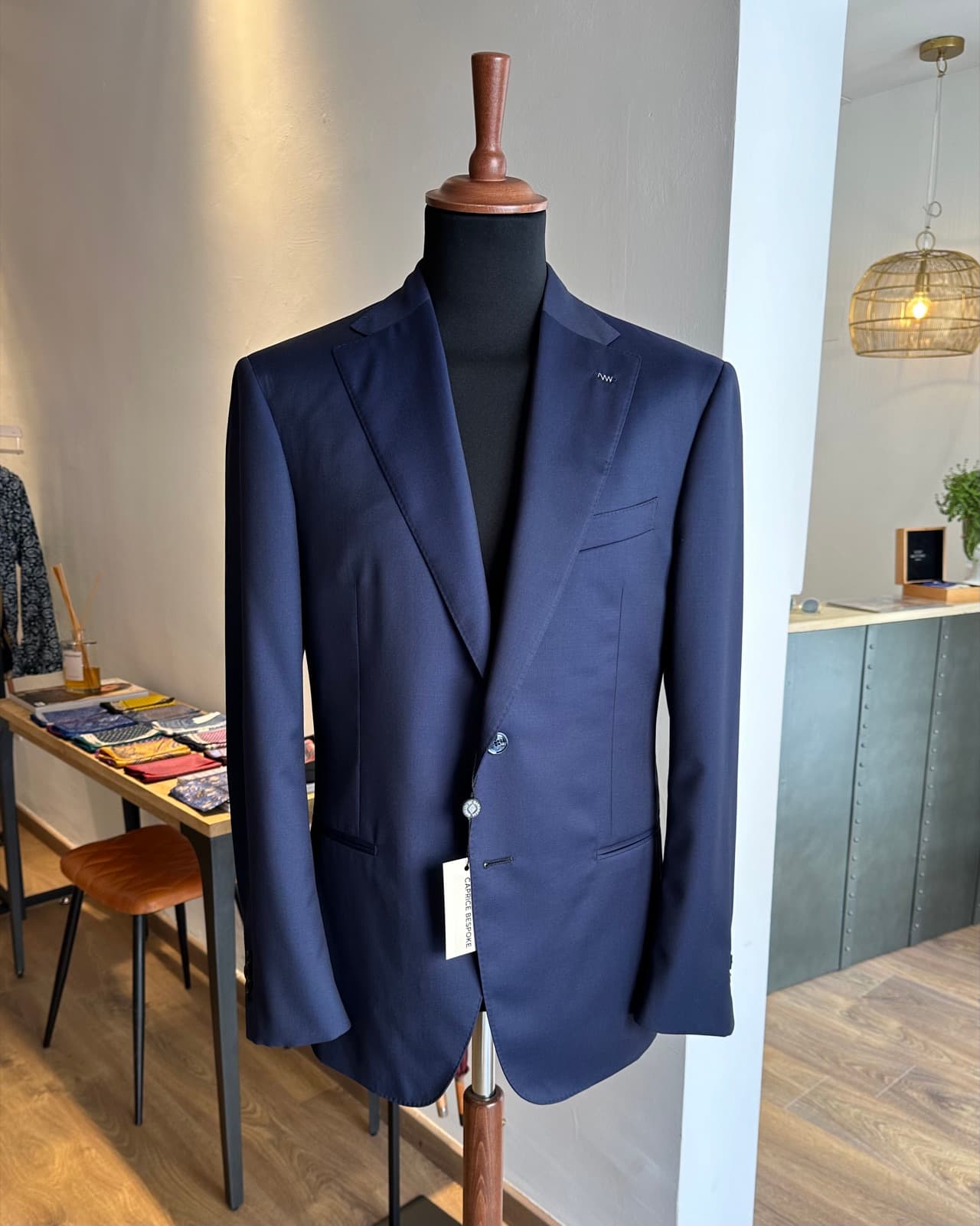 A navy tailored jacket on the shop floor beside fabric books.